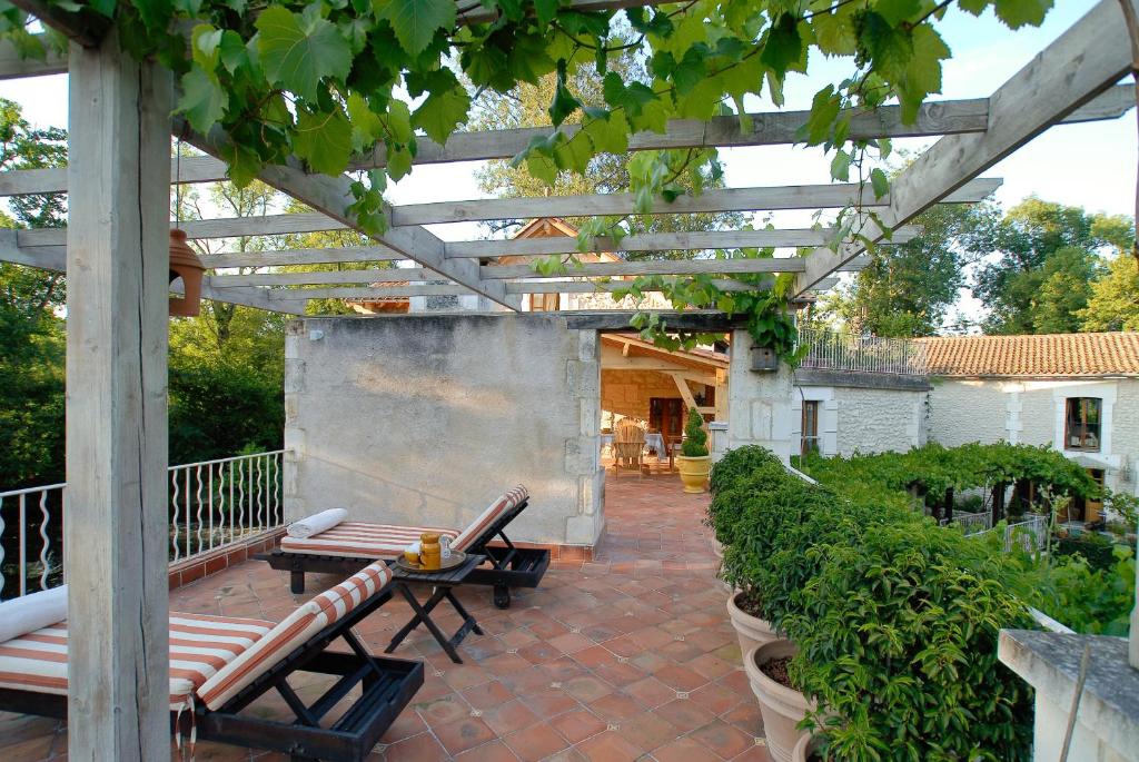 a patio with a wooden pergola and benches at Moulin De Larcy in Ribérac