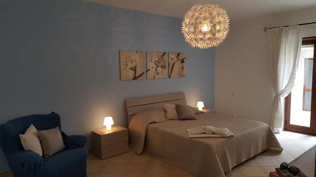 a bedroom with a bed and a chair and a chandelier at Casa Sofia in Caltabellotta