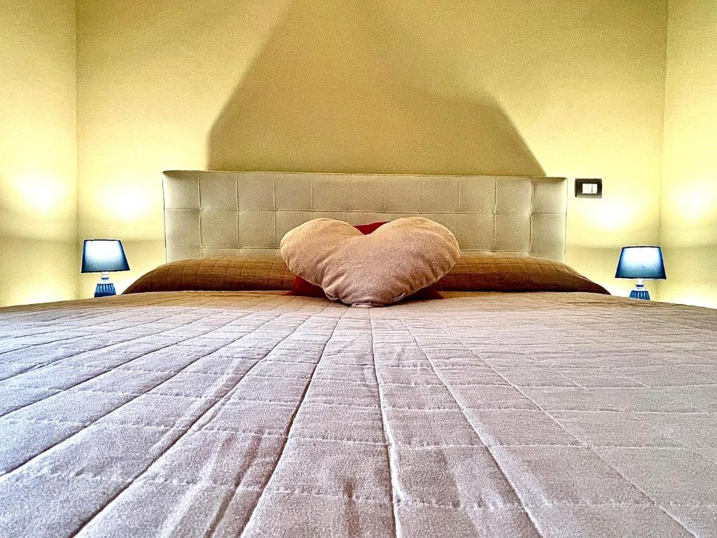 a bed with a pillow laying on top of it at Rosso Apartment in Alba