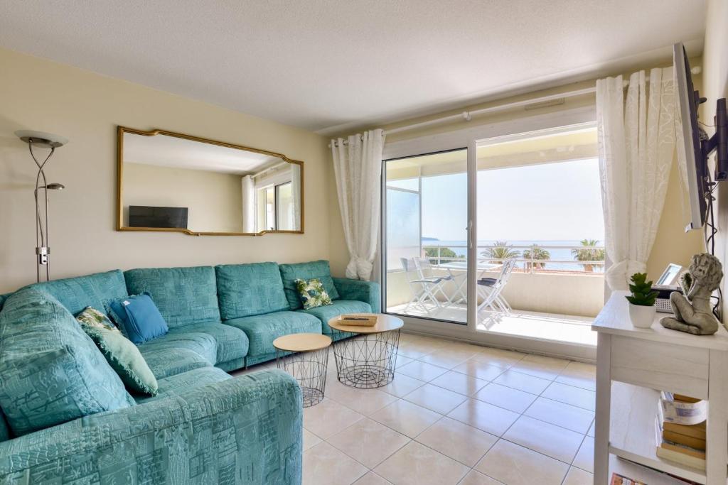 un salon avec un canapé bleu et une grande fenêtre dans l'établissement T3 avec terrasse vue sur mer à 400m de la plage, à Nice