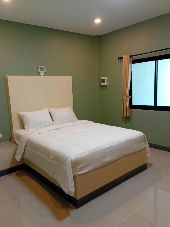 a bedroom with a large white bed with a window at Fairy Resort - แฟรี่รีสอร์ท in Ban Tha Thon