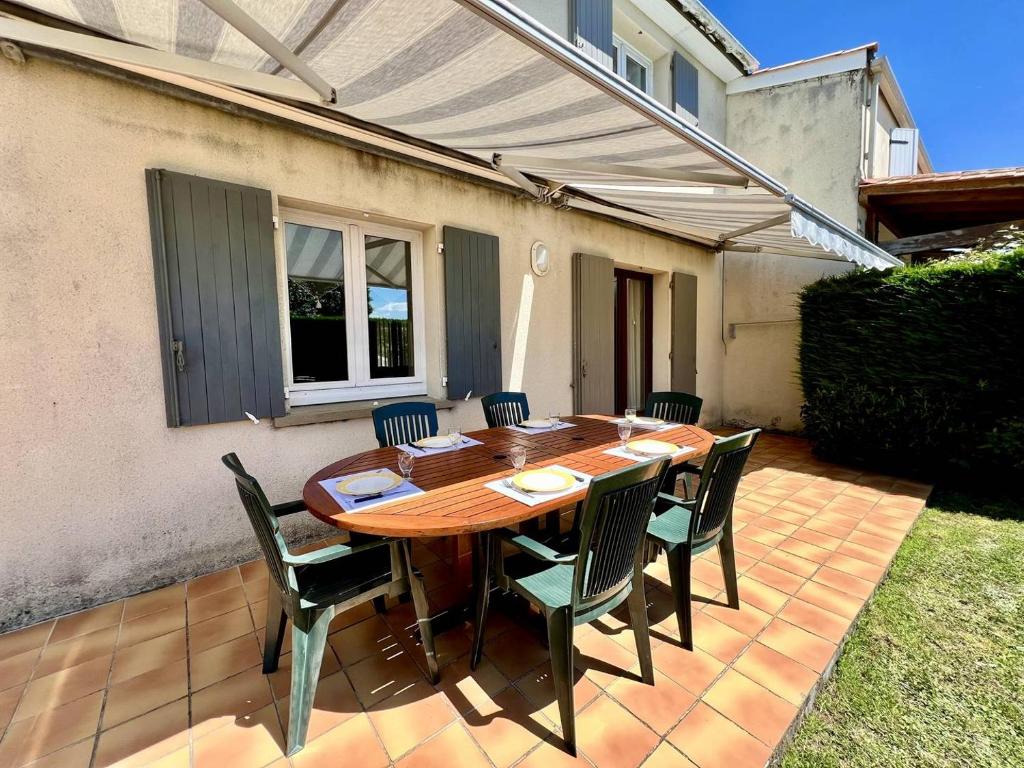 ein Holztisch und Stühle auf einer Terrasse in der Unterkunft Maison 4 pièces 6 couchages La Brée Les Bains LBO000-071 in La Brée-les-Bains