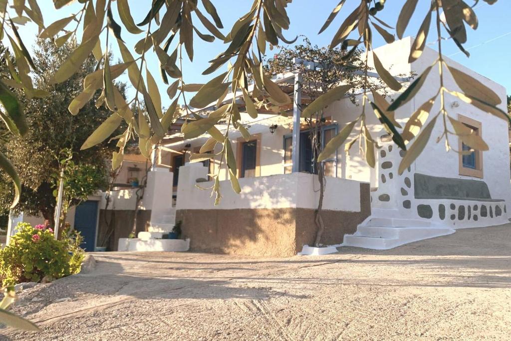 een wit huis met een boom ervoor bij Aloe House in Patmos