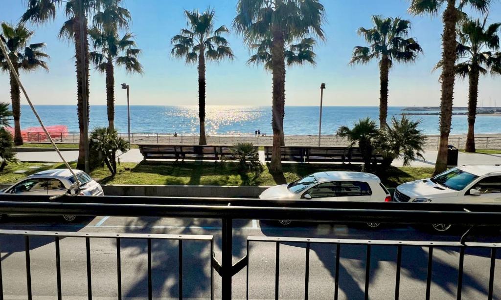 two cars parked next to the beach with palm trees at Trilocale fronte mare in Varazze