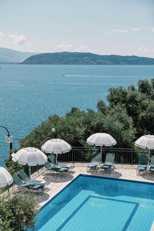 a swimming pool with chairs and umbrellas next to the water at White House Apartment in Kalami
