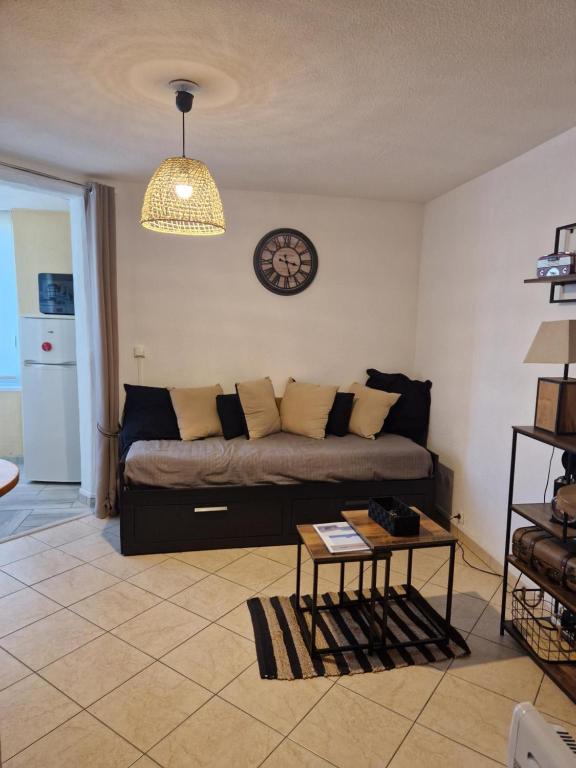 un salon avec un canapé et une horloge au mur dans l'établissement Les Sablettes, Soleil Et Douceur I, à La Seyne-sur-Mer