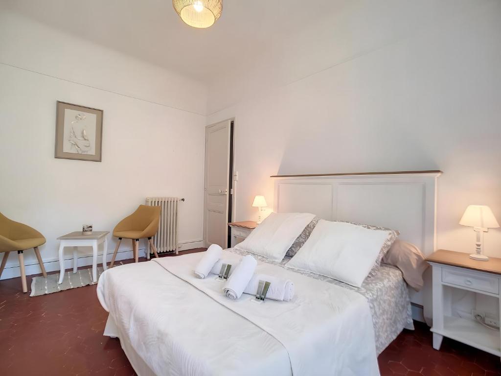 une chambre avec un lit blanc et deux chaises dans l'établissement Toulon Soleil Et Douceur ll, à Toulon