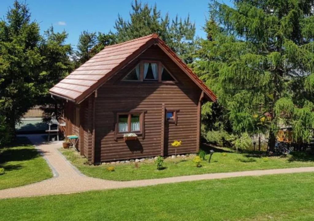 a small wooden cabin in a yard with trees at Domki na Mazurach - Rybical 65 in Ryn