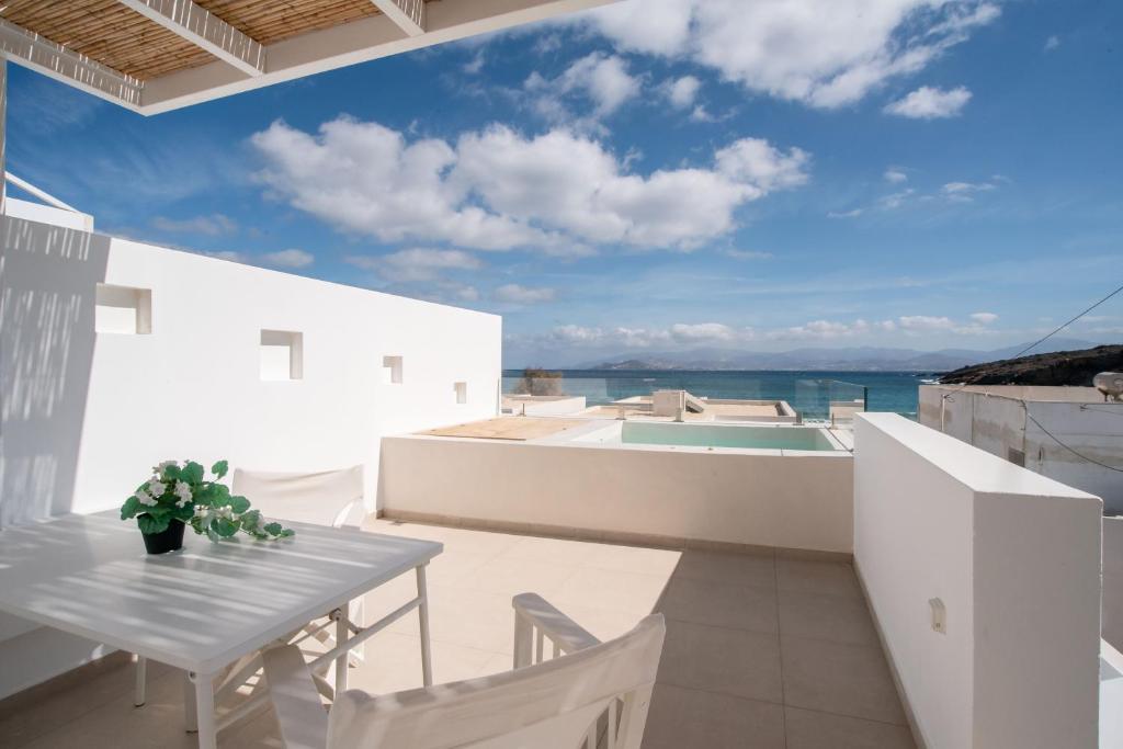 a balcony with a table and chairs and a view of the ocean at Deluxe Maisonette With Private Jacuzzi in Glifades