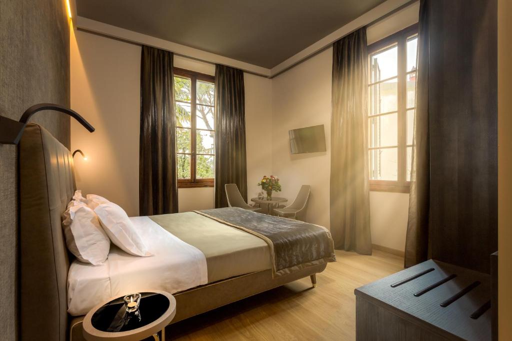 um quarto com uma cama, uma mesa e janelas em Soggiorno Campos em Florença