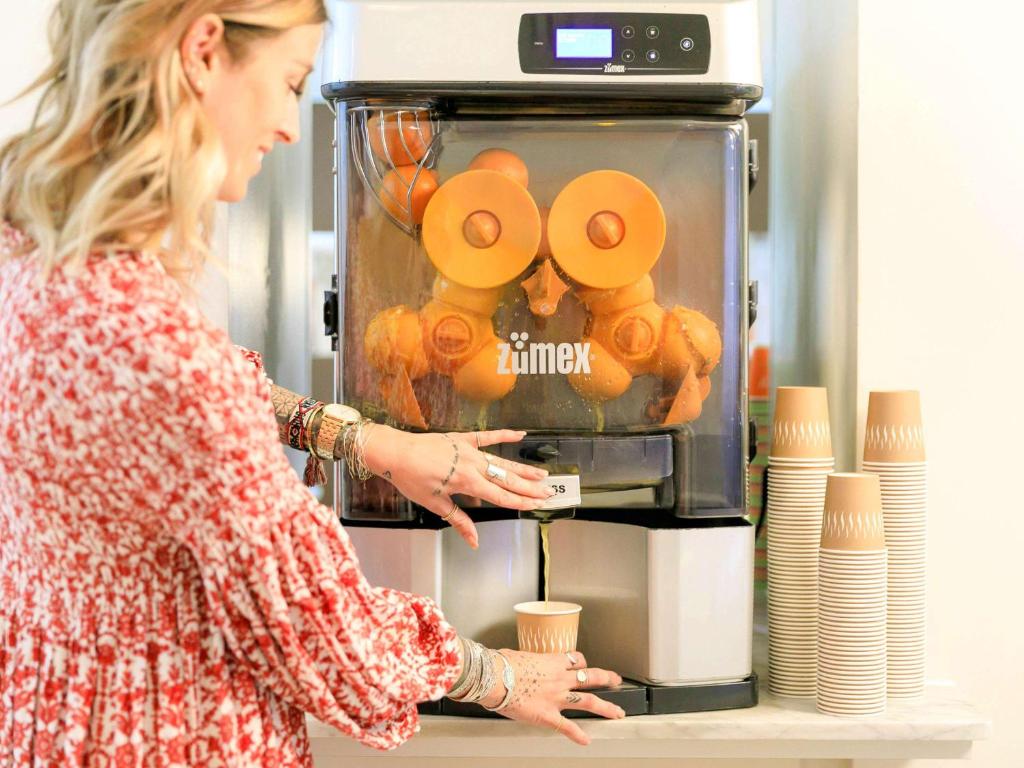 a woman standing in front of a coffee machine at Ibis Styles Menton Centre in Menton