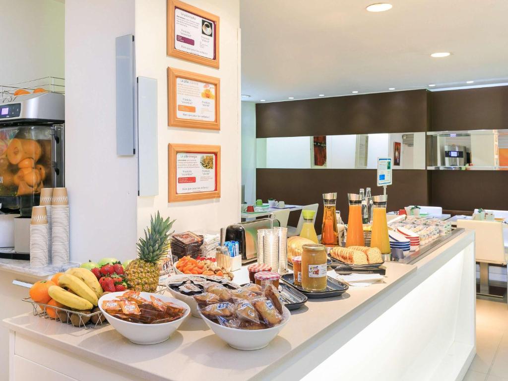 a buffet with bowls of fruit and vegetables on a counter at Ibis Styles Menton Centre in Menton