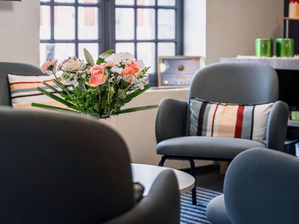 un vase de fleurs dans une pièce avec deux chaises dans l'établissement ibis Styles Vannes Gare Centre, à Vannes