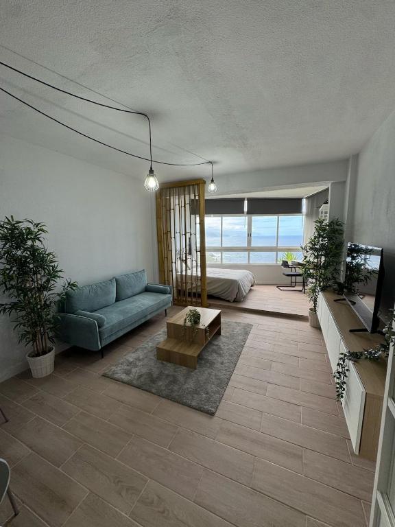 a living room with a blue couch and a bed at Ocean Panorama in Puntillo del Sol