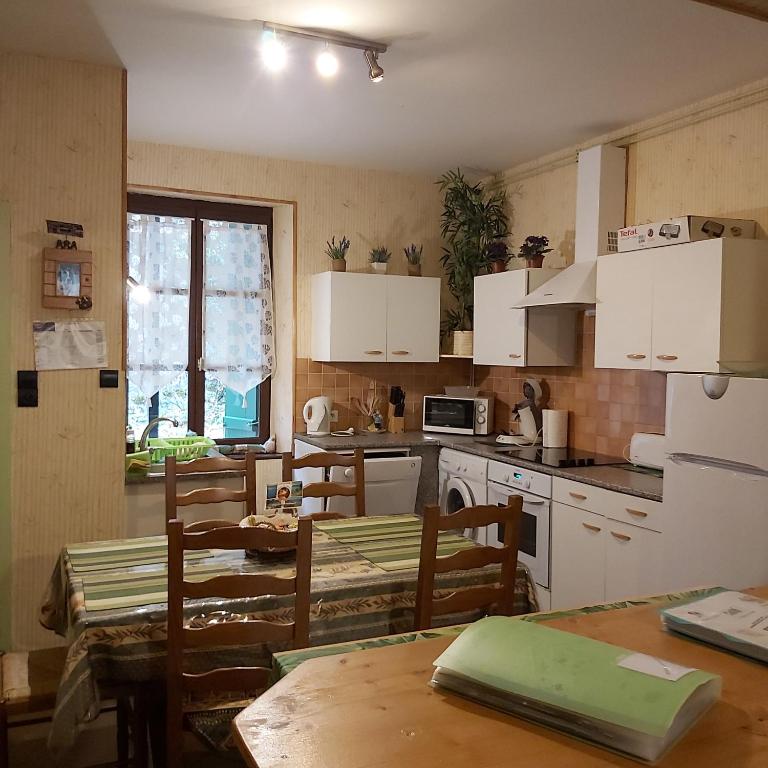 une cuisine avec des armoires blanches et une table et des chaises dans l'établissement appartement chez Chantal RDC 60m2 GERARDMER, à Gérardmer