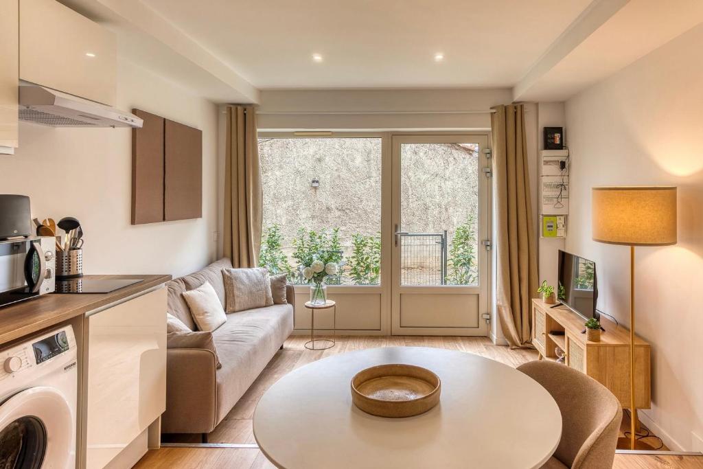 een woonkamer met een bank en een tafel bij L’Epicéa - RDJ duplex proche métrohôpital in Oullins