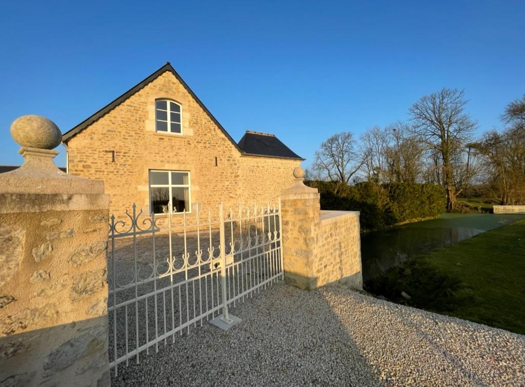 une maison en briques avec un portail en face de celle-ci dans l'établissement Gîte de La Baumée, à Hiesville