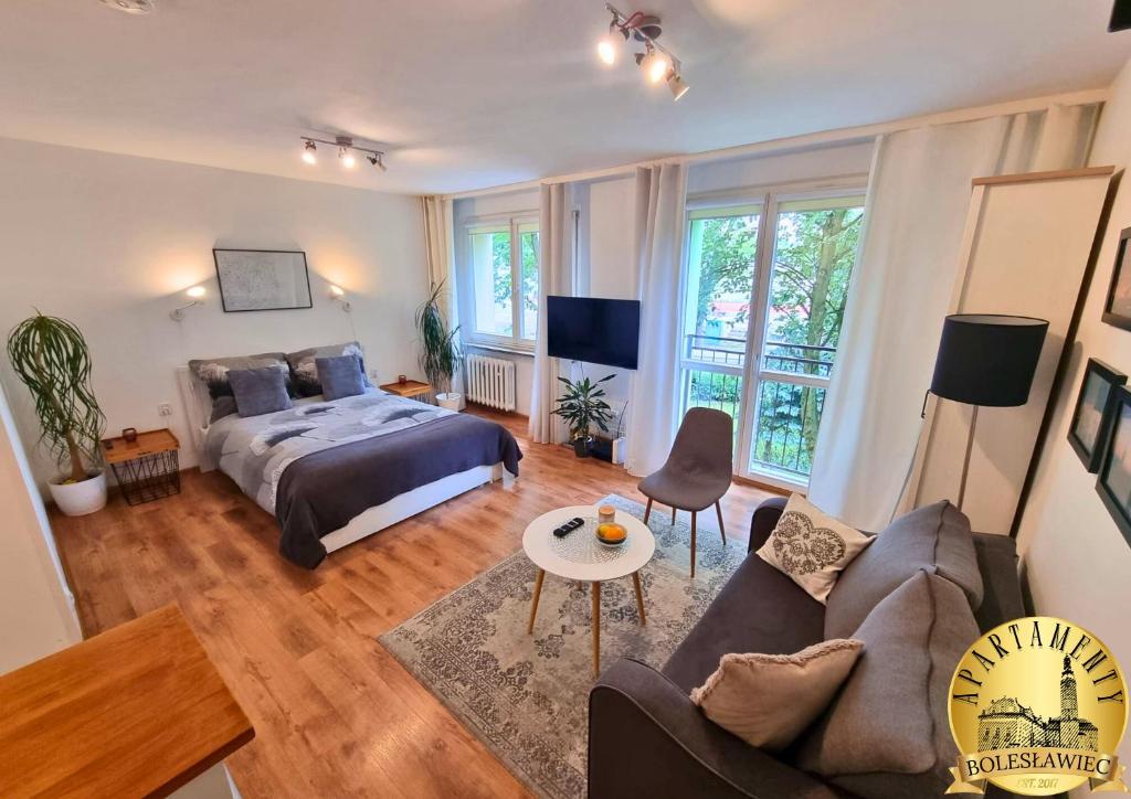 a bedroom with a king sized bed and a couch at Apartamenty Bolesławiec Spółdzielcza Free parking in Bolesławiec