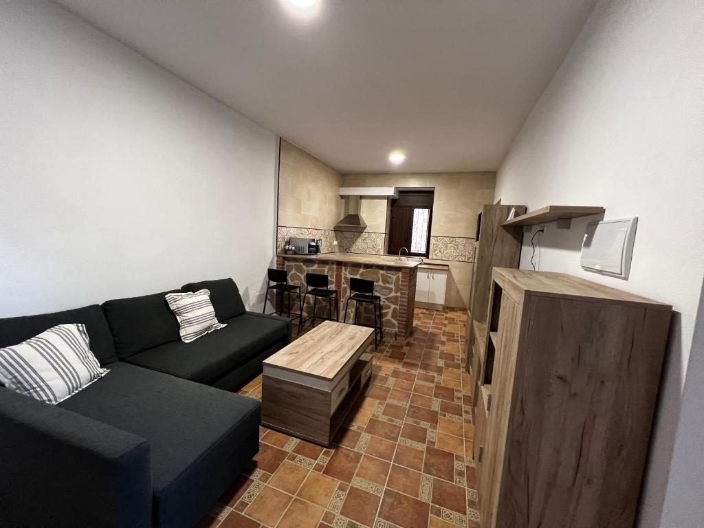 a living room with a black couch and a kitchen at Pósito de Don Juan in Fuente Victoria