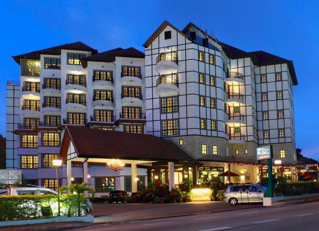 a large white building with cars parked in front of it at Hotel De' La Ferns, Cameron Highlands in Cameron Highlands
