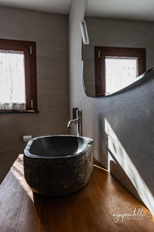 un bagno con un grande lavandino in pietra su un pavimento in legno di La Terrazza di Tranci a Calice al Cornoviglio