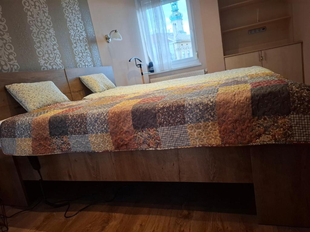 a bed with a quilt on it in a bedroom at Soproniutas CentROOM Apartman in Sopron