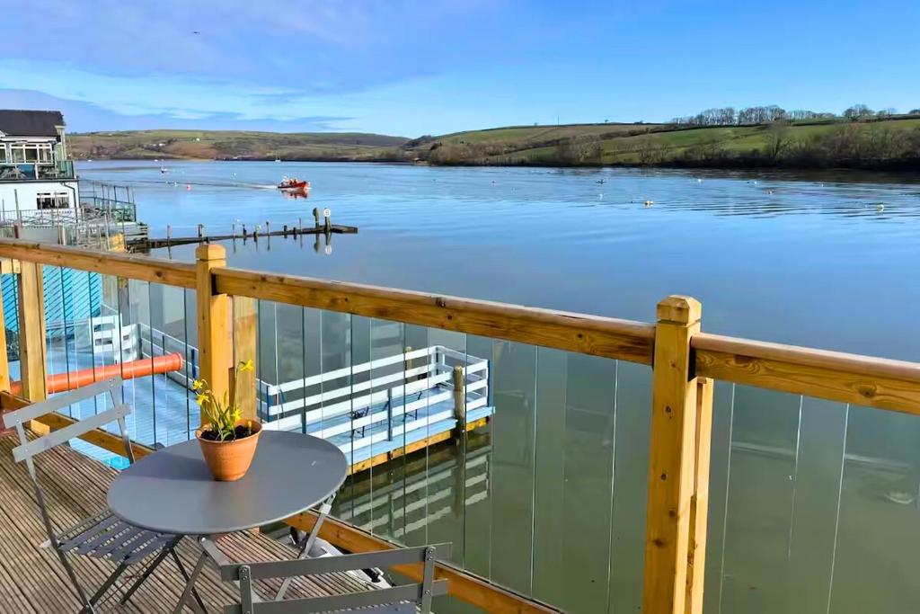 Una mesa en un balcón con vista a un río. en Estuary's Rest Studio Apartment at Galwad Y Mor, en Cardigan