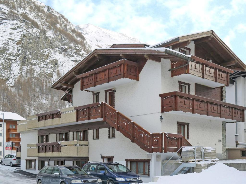 a building with wooden balconies and cars parked in the snow at Apartment Haus Quelle-2 by Interhome in Saas-Grund