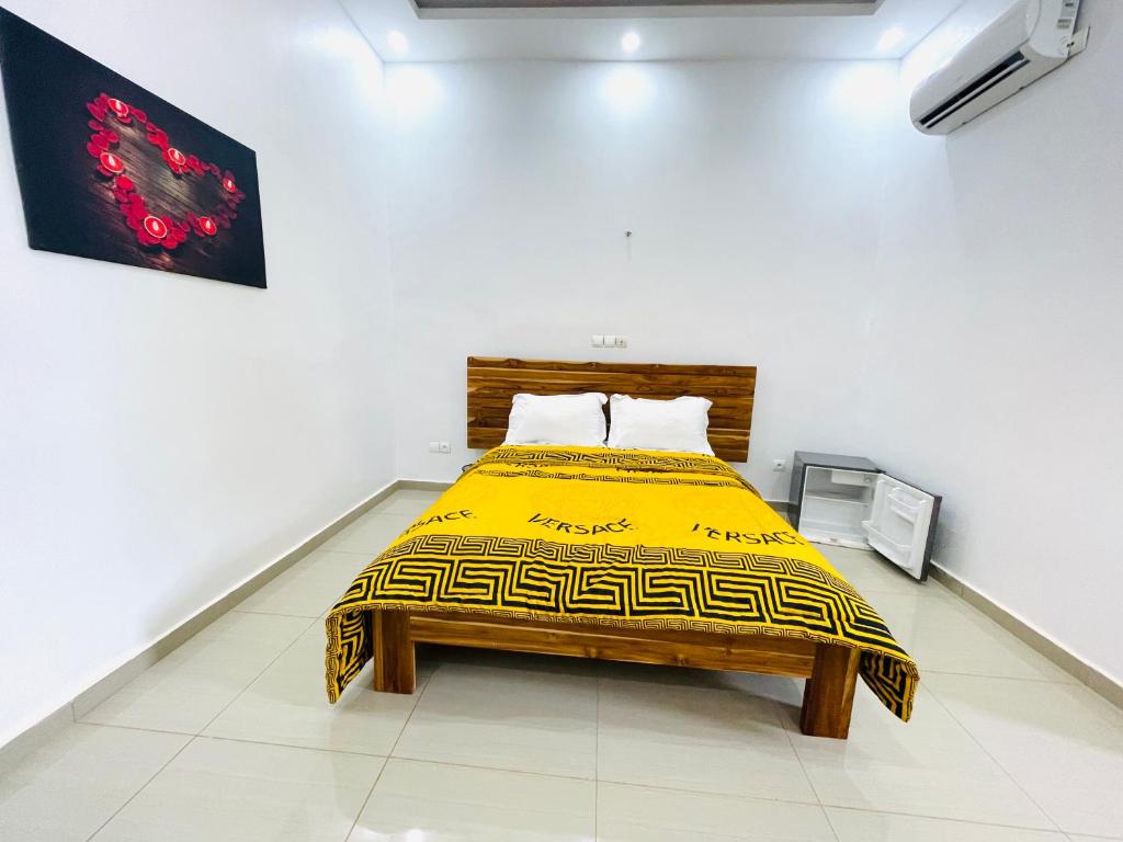 Résidences hôtels sibontour في ياموسوكرو: سرير في غرفة بيضاء مع بطانية صفراء