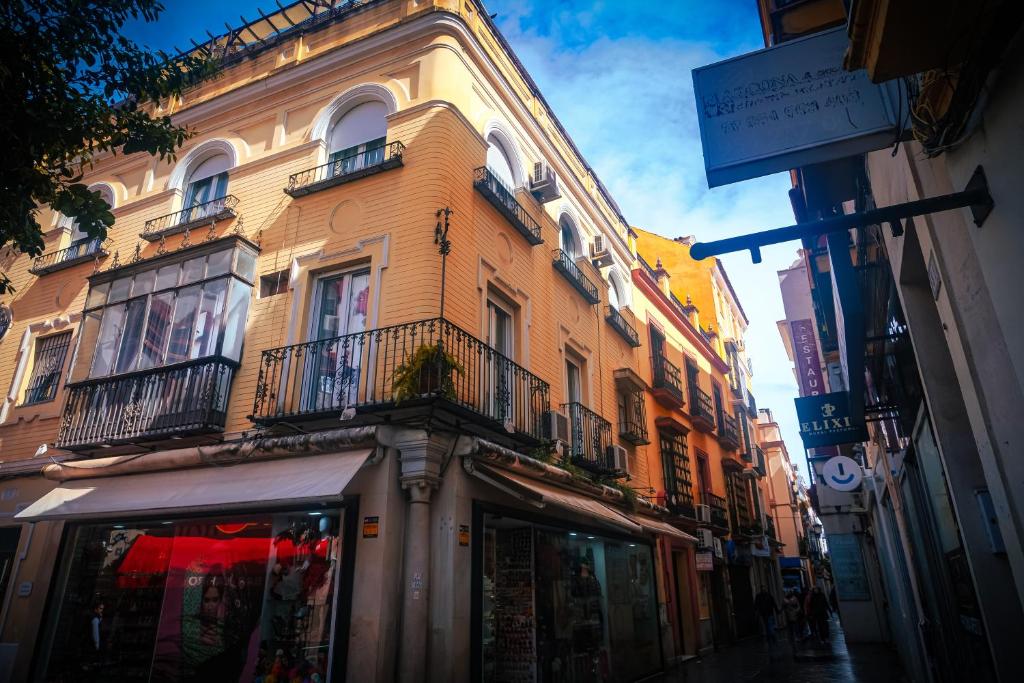a tall yellow building with balconies on a street at Casa San Roque in Seville