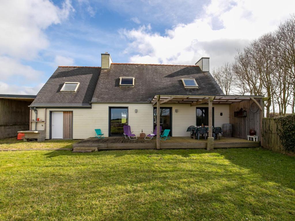 une maison avec une terrasse couverte et des chaises dans une cour dans l'établissement Holiday Home Le Nid Marin by Interhome, à Kerlouan
