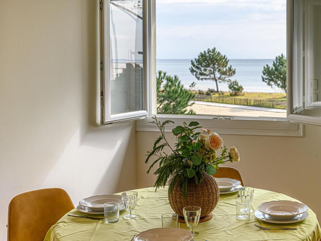 une table avec un vase de fleurs et une fenêtre dans l'établissement Apartment La Voilerie by Interhome, à Carnac