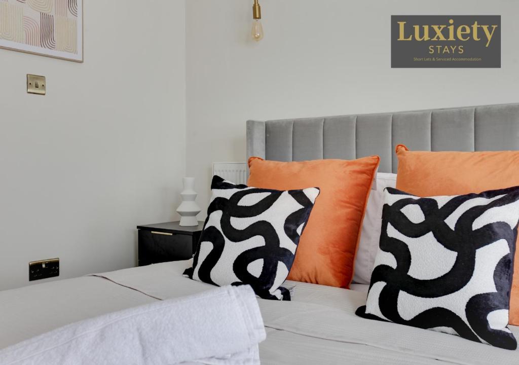 a bed with orange and black pillows on it at Sunny & Charming Studio City Centre Nr High Street by Luxiety Stays in Southend-on-Sea