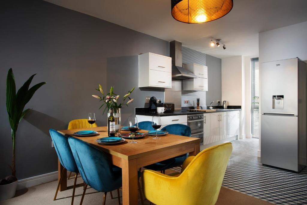 a kitchen with a wooden table and blue chairs at Plymouth Penthouse Apartment-Sea View-Sleeps 7- Habita Property in Plymouth
