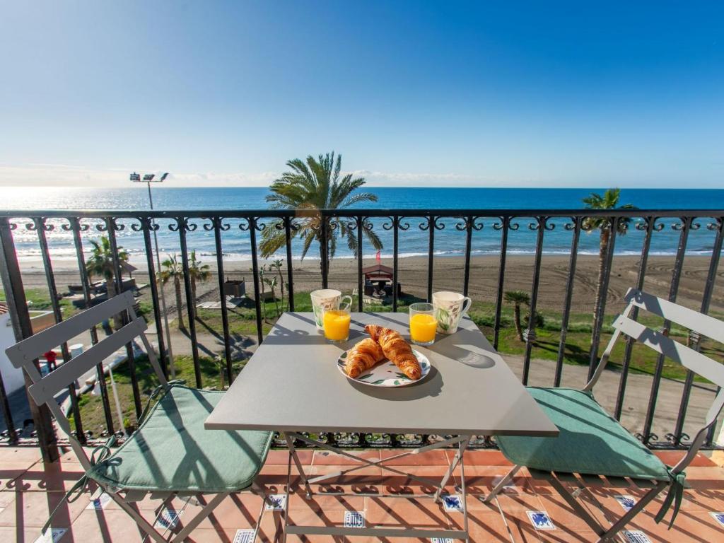 a table with a plate of food on a balcony with the beach at Apartment Rinconada beachfront by Interhome in Rincón de la Victoria