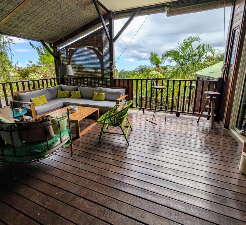 a screened in porch with a couch and a table at Villa Créole avec Jacuzzi à la Rivière in La Rivière