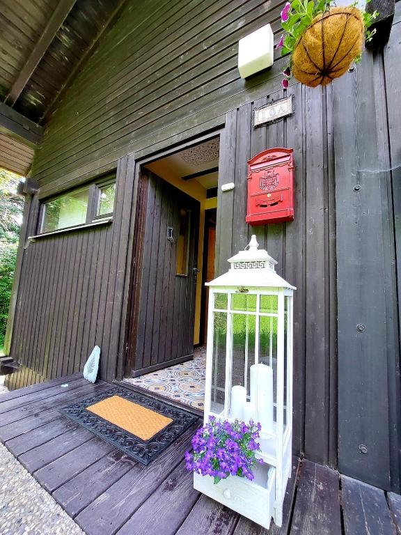 a house with a bird cage and flowers on a porch at Geographer`s Cottage II in Siegsdorf