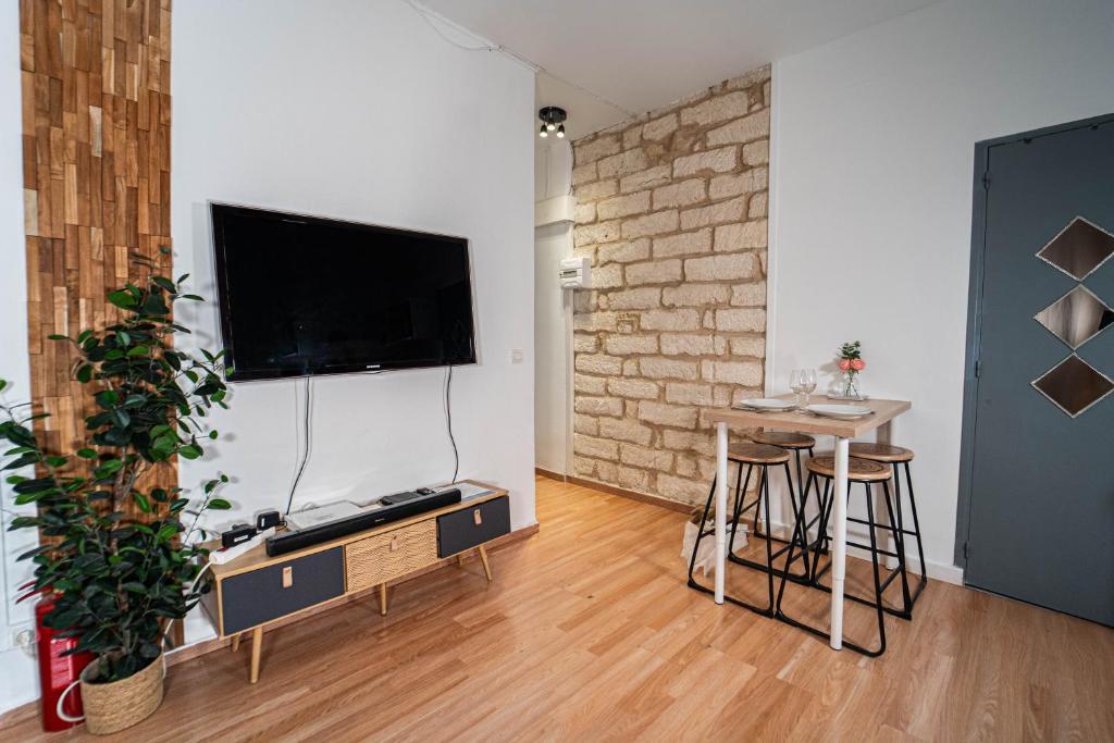un salon avec une télévision à écran plat sur un mur dans l'établissement T2 Centre Ville à 2 min Gare St-Roch avec climatisation, à Montpellier