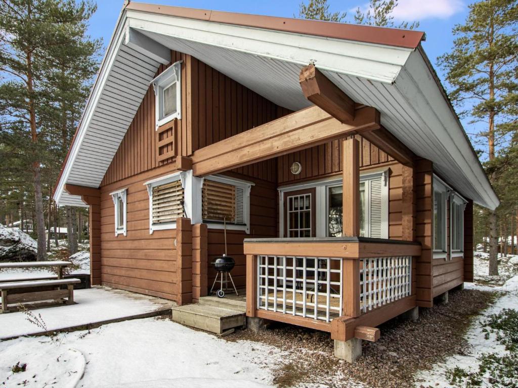 a tiny house with a porch in the snow at Holiday Home Puolukka 2 by Interhome in Isnäs