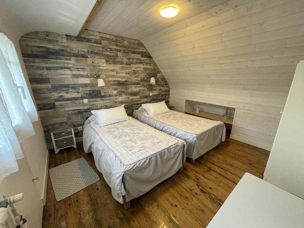 two beds in a room with a wooden wall at Maison de pêcheur in Perros-Guirec