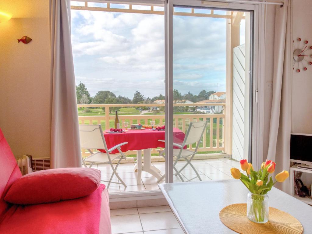 ein Wohnzimmer mit Tisch und Balkon in der Unterkunft Apartment L'Orée du Golf-2 by Interhome in Pornic