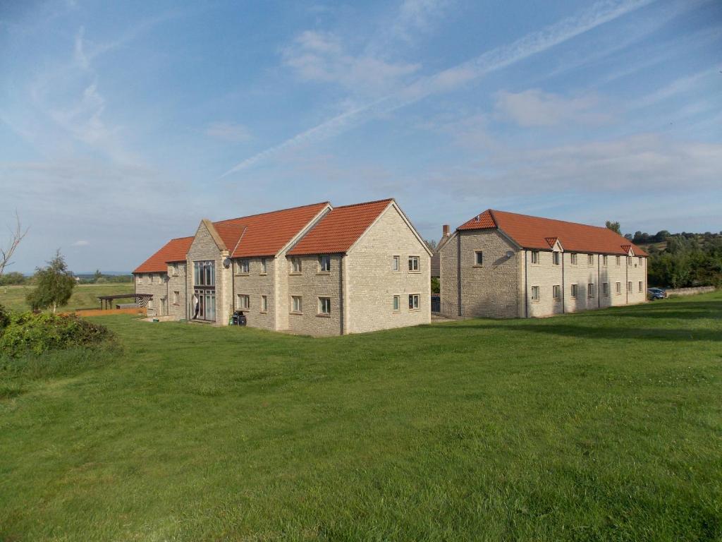 a large house with red roofs on a green field at Canons Court Mews in Wotton-under-Edge