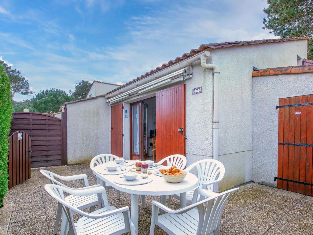 Una mesa blanca y sillas en un patio. en Holiday Home Hameau de Talaris-18 by Interhome, en La Palmyre