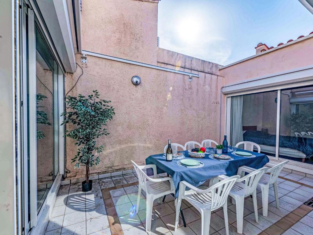 une table avec des chaises blanches et un chiffon de table bleu dans l'établissement Holiday Home Les Sirènes by Interhome, au Barcarès