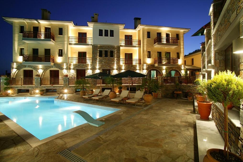 a hotel with a swimming pool in front of a building at Maritsas Hotel & Suites in Portaria