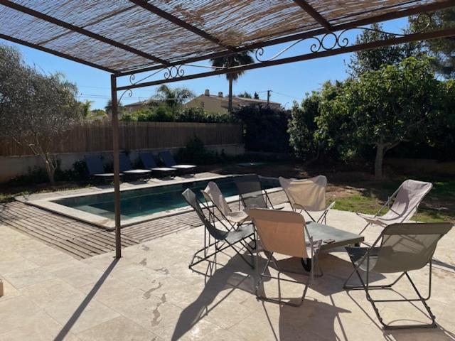 une terrasse avec des chaises, une table et une piscine dans l'établissement Maison proche de la plage, à Six-Fours-les-Plages