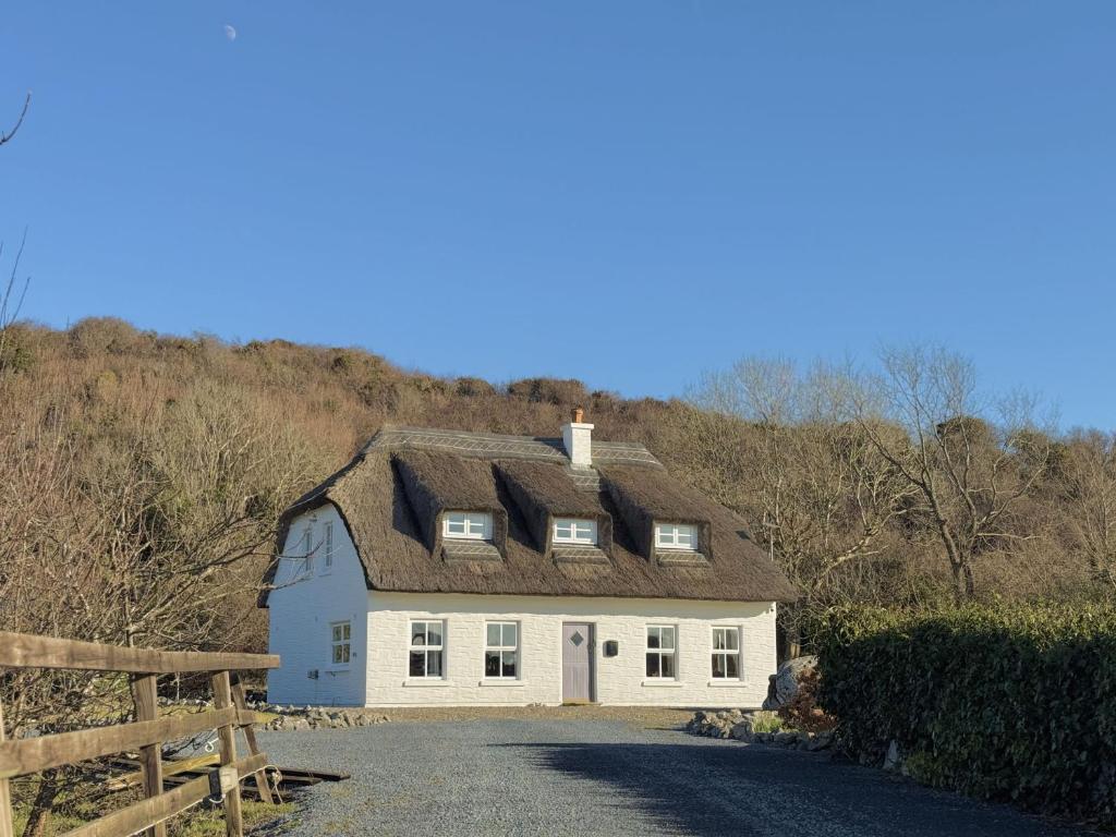 a white house with a roof on a road at Stargazers Cottage in Doolin