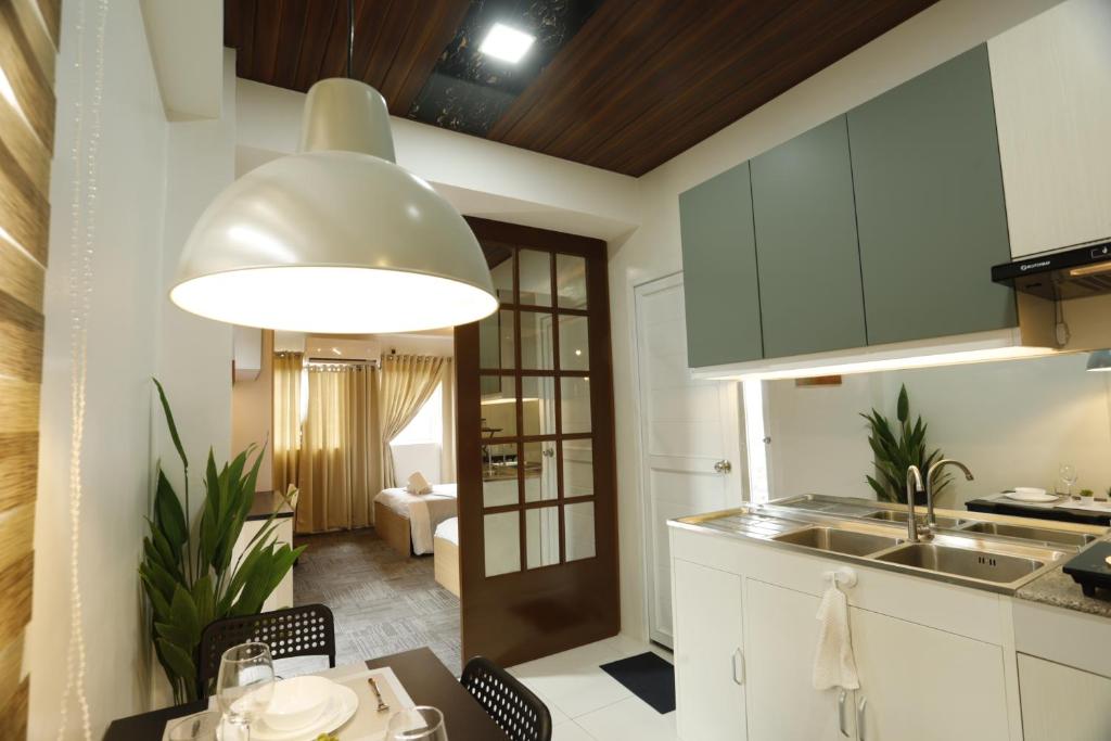 a kitchen with white cabinets and a large light fixture at La Joya Suite in Naga
