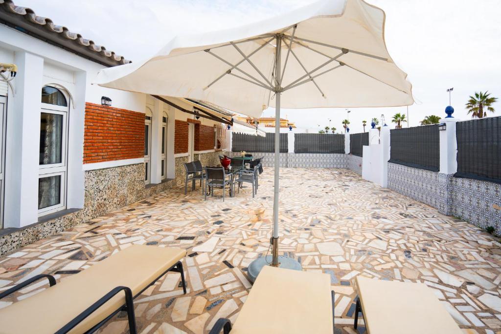 een parasol op een patio met tafels en stoelen bij A&N Refugio del Mar in Torre del Mar