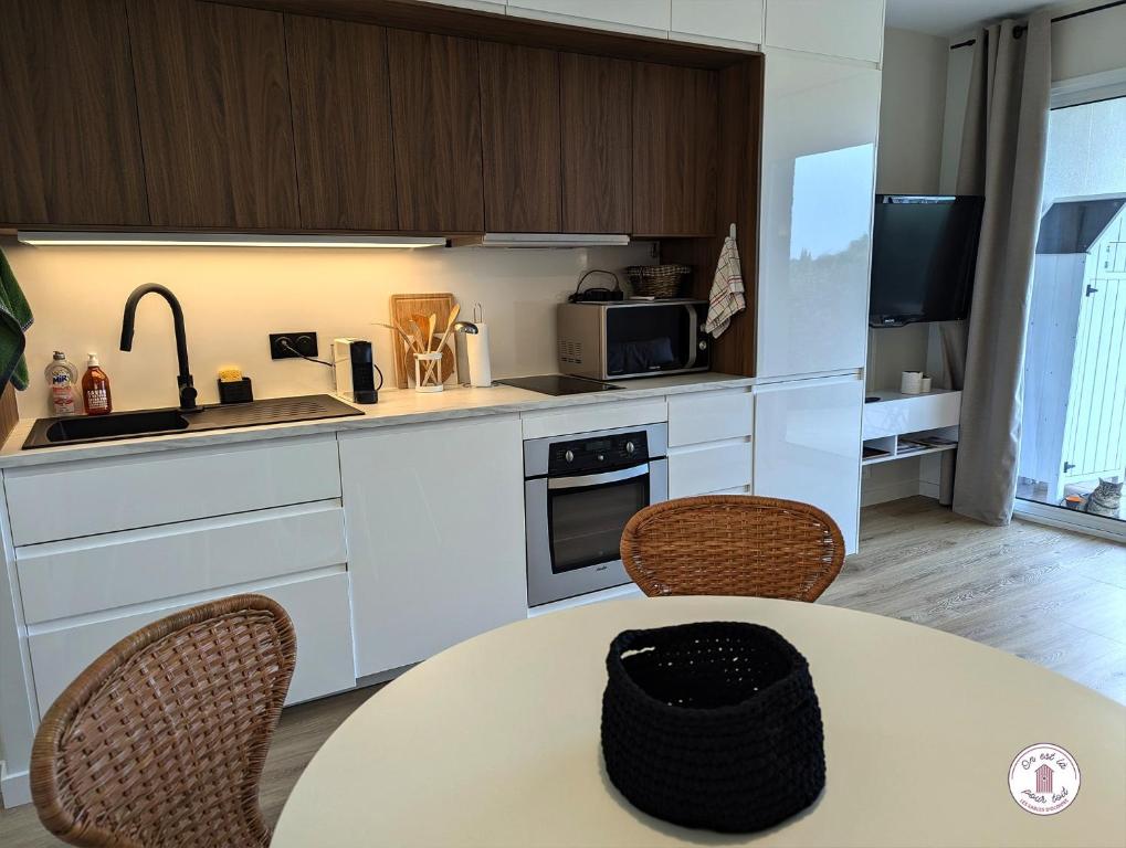 - une cuisine avec une table, 2 chaises et un évier dans l'établissement Escale aux Sables, à Saint-Jean-dʼOrbetiers